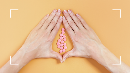 hands surrounding pink pills on orange background 