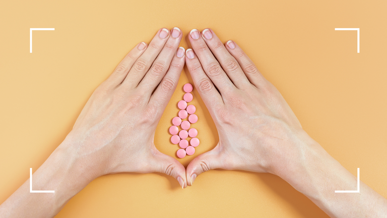 hands surrounding pink pills on orange background