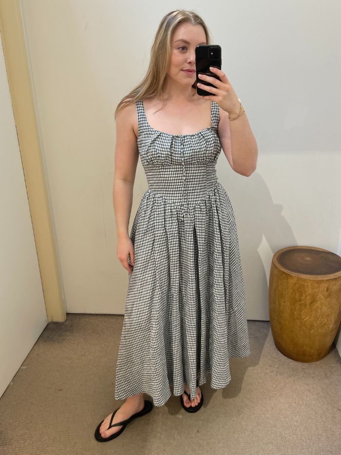 Woman wears gingham print dress from Reformation