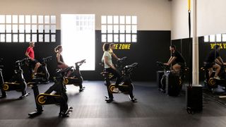 Group of women cycling in a workout class, looking at the instructor at the front of the room