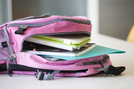 Pink bookbag with laptop and notebooks inside - stock photo