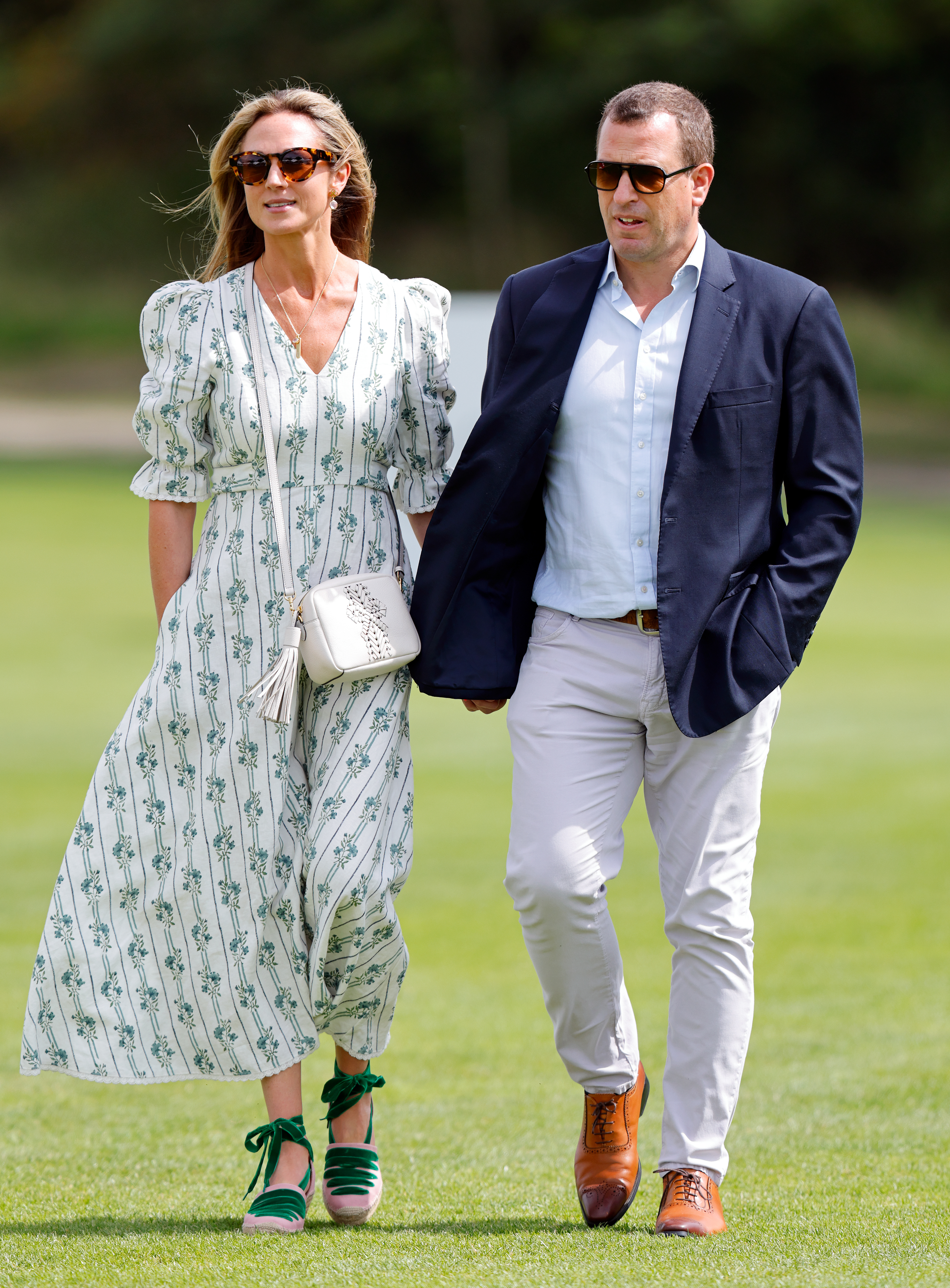 Harriet Sperling and Peter Phillips walking along grass in sunglasses