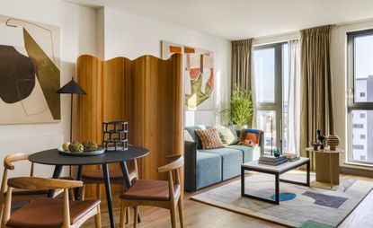 Living interior at apartment building in Tottenham Hale with large windows, blue couch and wood floors