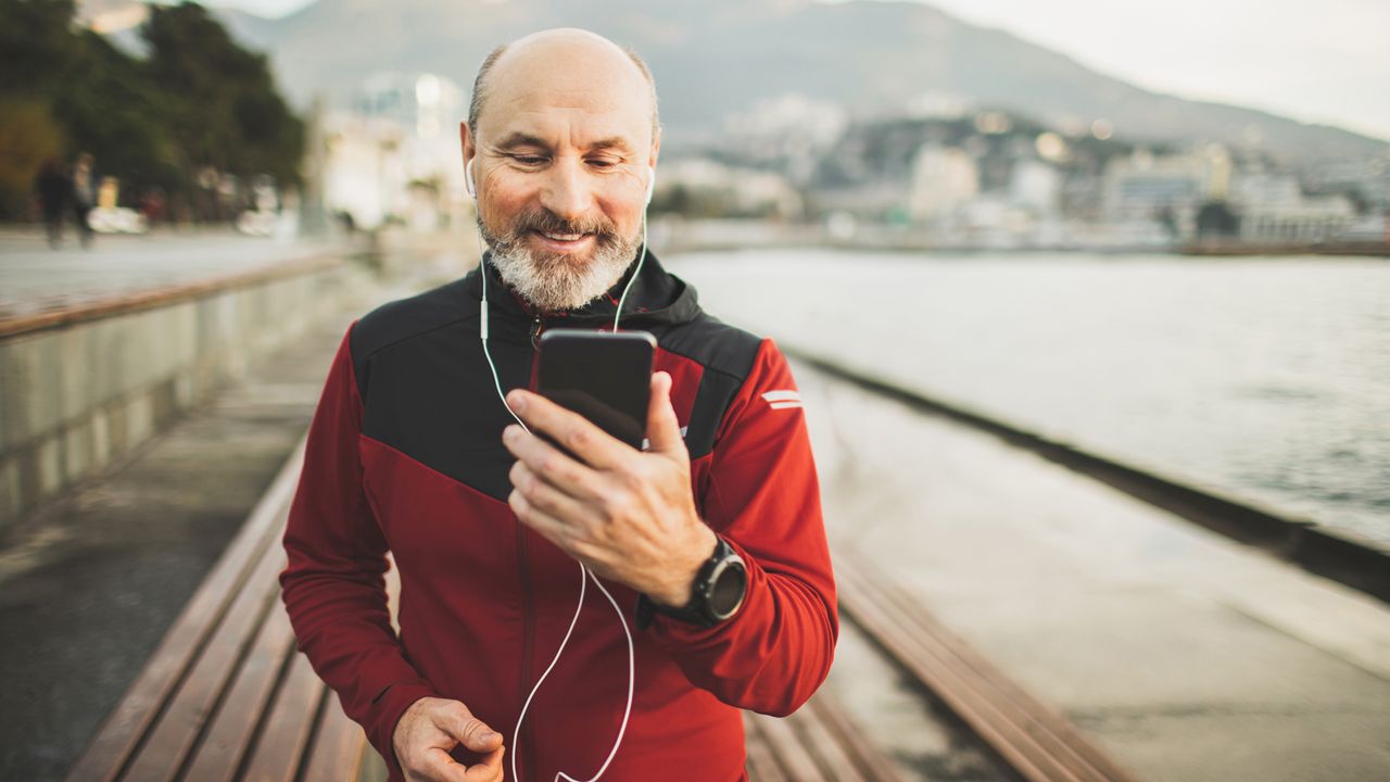 Older man tracking his run on his phone outside