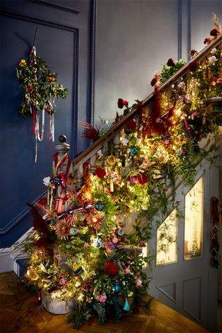 A hallway with black wall decor, white painted front door and Christmas foliage decor on banister