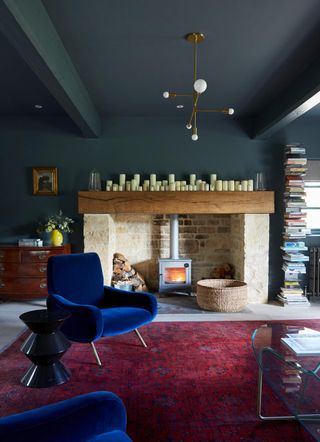 red living room rug below dark blue walls and ceiling, with a royal blue armchair