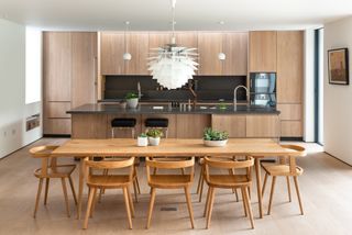 Wood kitchen with island and dining table and chairs with pendant light above