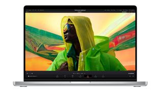 A man in a bright yellow and green jacket is displayed on the 16-inch screen of the MacBook Pro.