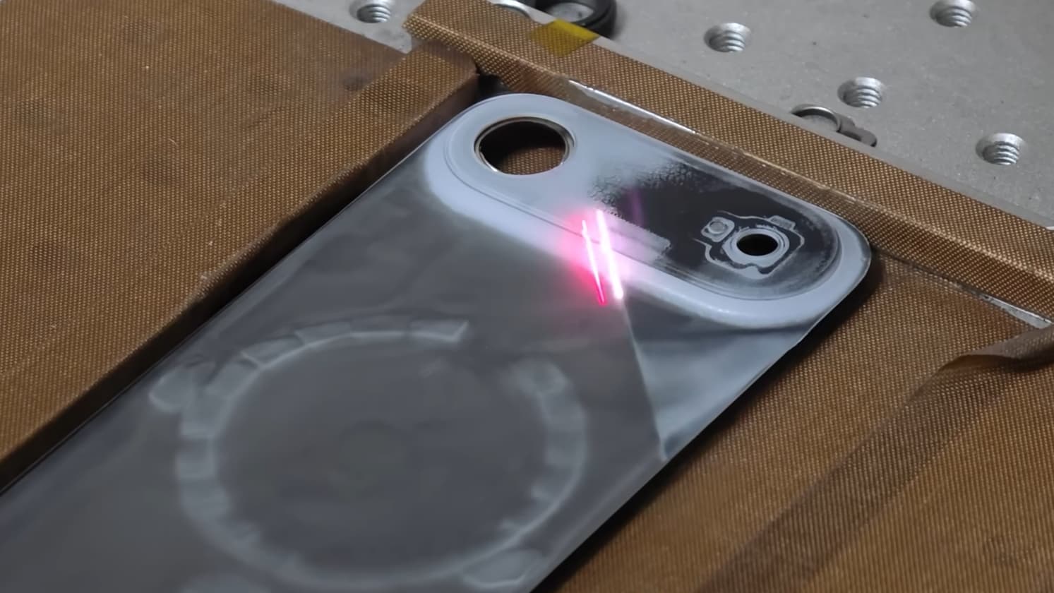 The back case of an iPhone Air being laser stripped to remove its paint.