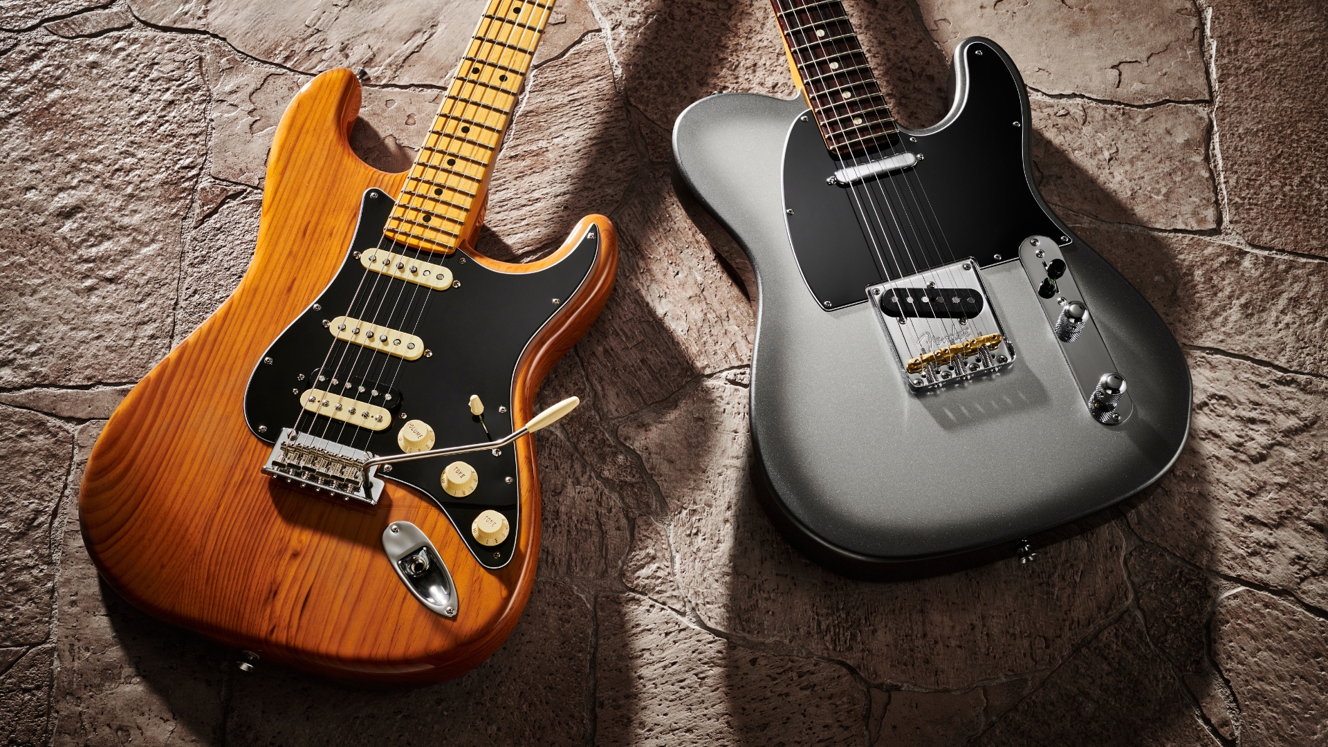 Two Fender American Professional II electric guitars lying on the ground