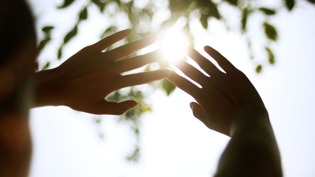 woman holding her hands up to the sun