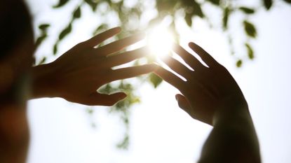 woman holding her hands up to the sun