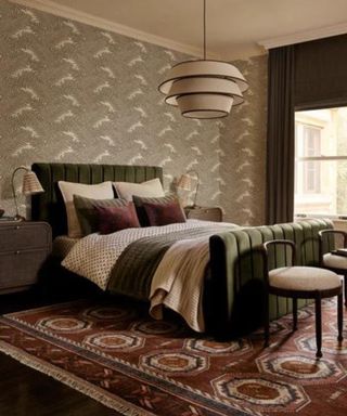 Bedroom with floral wallpaper, green velvet bed and red patterned rug