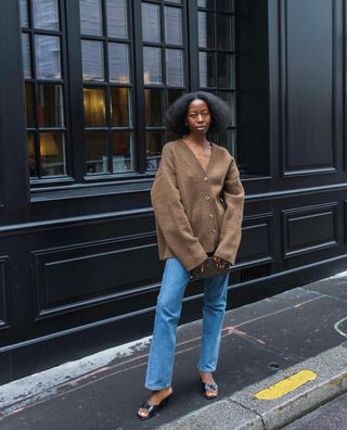 Sylvie Mus wears a brown cardigan and straight leg jeans