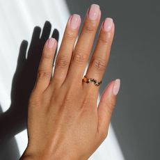 A photo of Iram Shelton's hands with a square manicure with a sheer pink nail colour on top