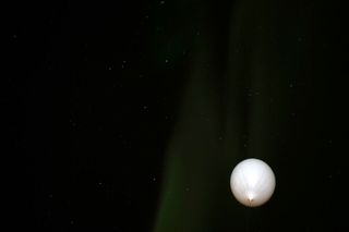 An instrument-laden weather balloon rises into the Alaskan auroras on April 12, 2012.