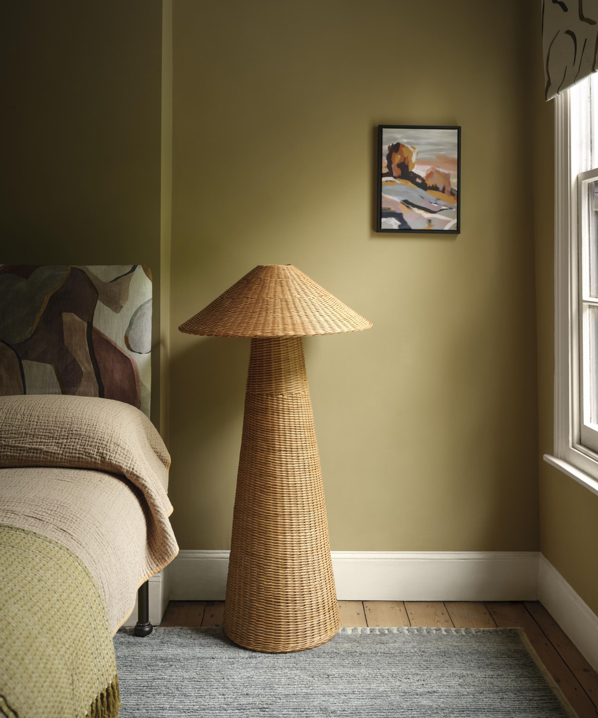 Warm and inviting bedroom with earthy tones, featuring a unique woven floor lamp beside a bed with a textured quilt