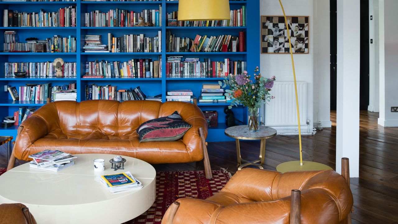 Living room with built in blue bookcase and brown leather sofa and armchairs