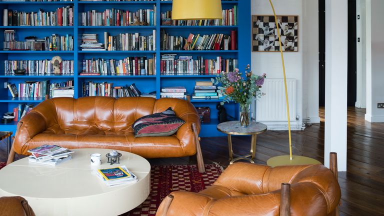 Living room with built in blue bookcase and brown leather sofa and armchairs