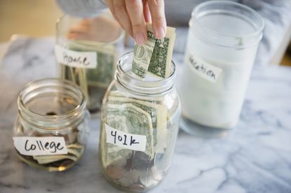 Mixed race woman saving money in jars