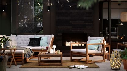 an outdoor seating area with IKEA's namarro modular garden sofa and chair and coffee table with string lights above and a portable table lamp sits on the coffee table