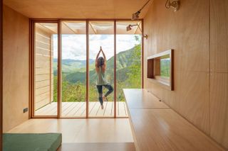 woman doing yoga on the deck of a wooden tiny house