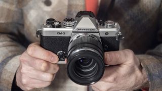 OM System OM-3 mirrorless camera in the hand, 12-45mm F4 Pro lens attached