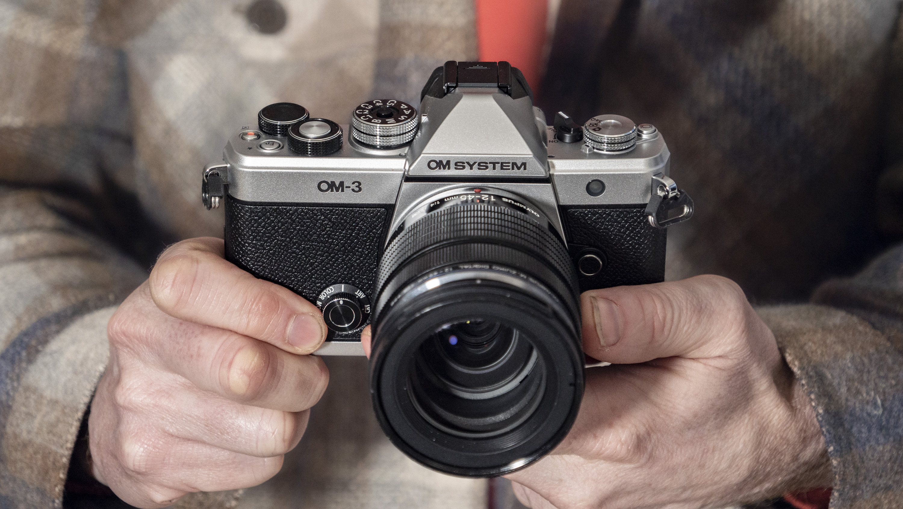 OM System OM-3 mirrorless camera in the hand, 12-45mm F4 Pro lens attached