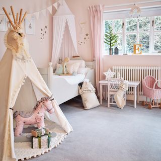 a child's bedroom with play tent and pretty canopy over a cot bed