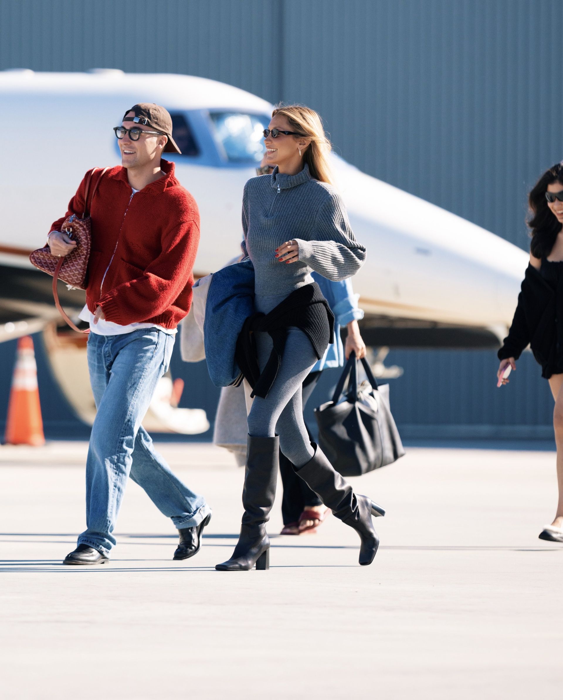 Bella Hadid arrives at the airport wearing grey leggings with a matching grey knit and black knee-high boots.