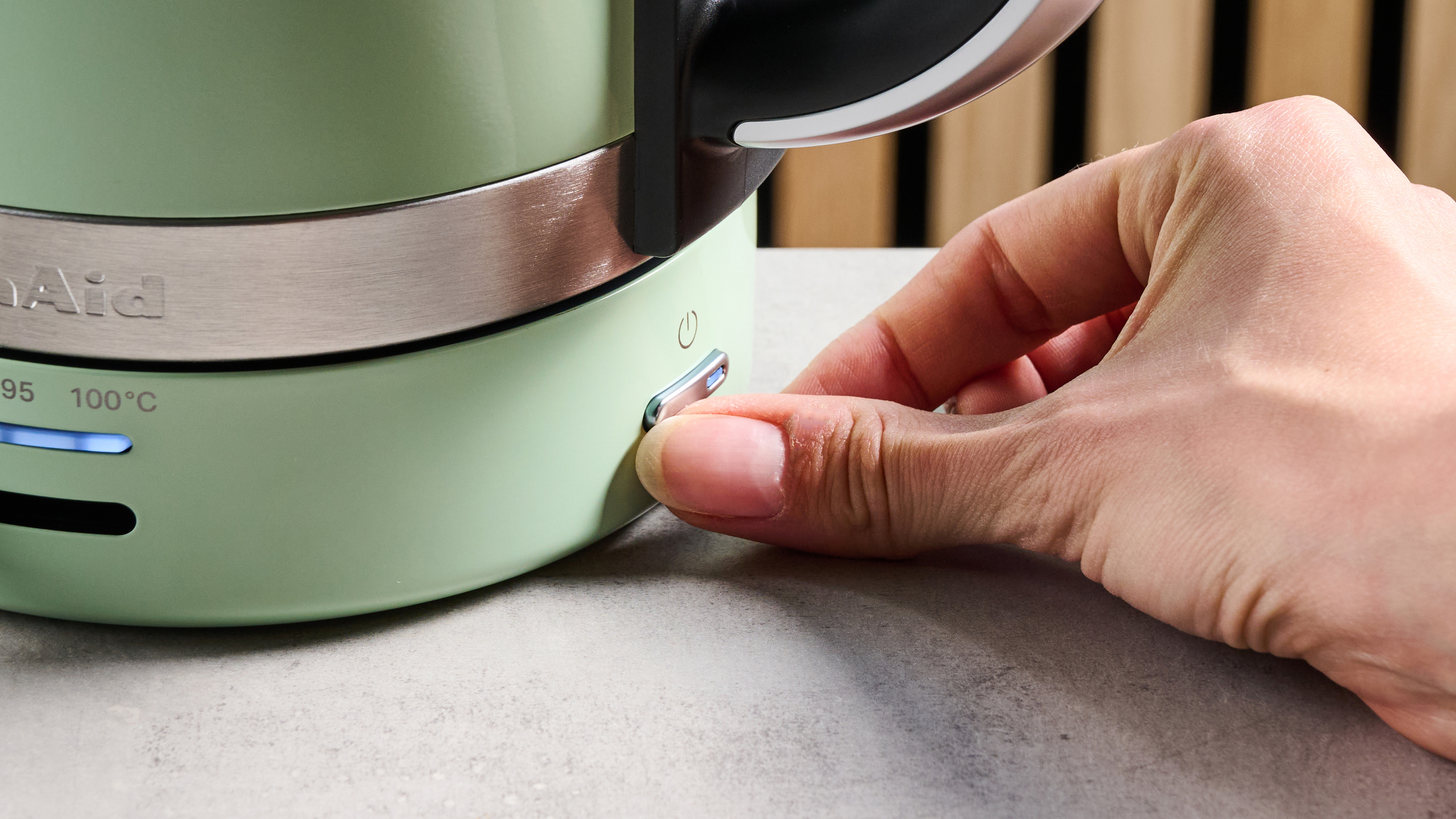the kitchenaid 1.7L kettle in pistachio photographed on a white marble counter with a blue background