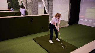 Woman golfer hitting into simulator