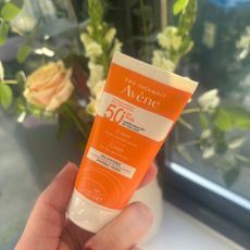 a hand holding a tube of avene very high protection cream spf50