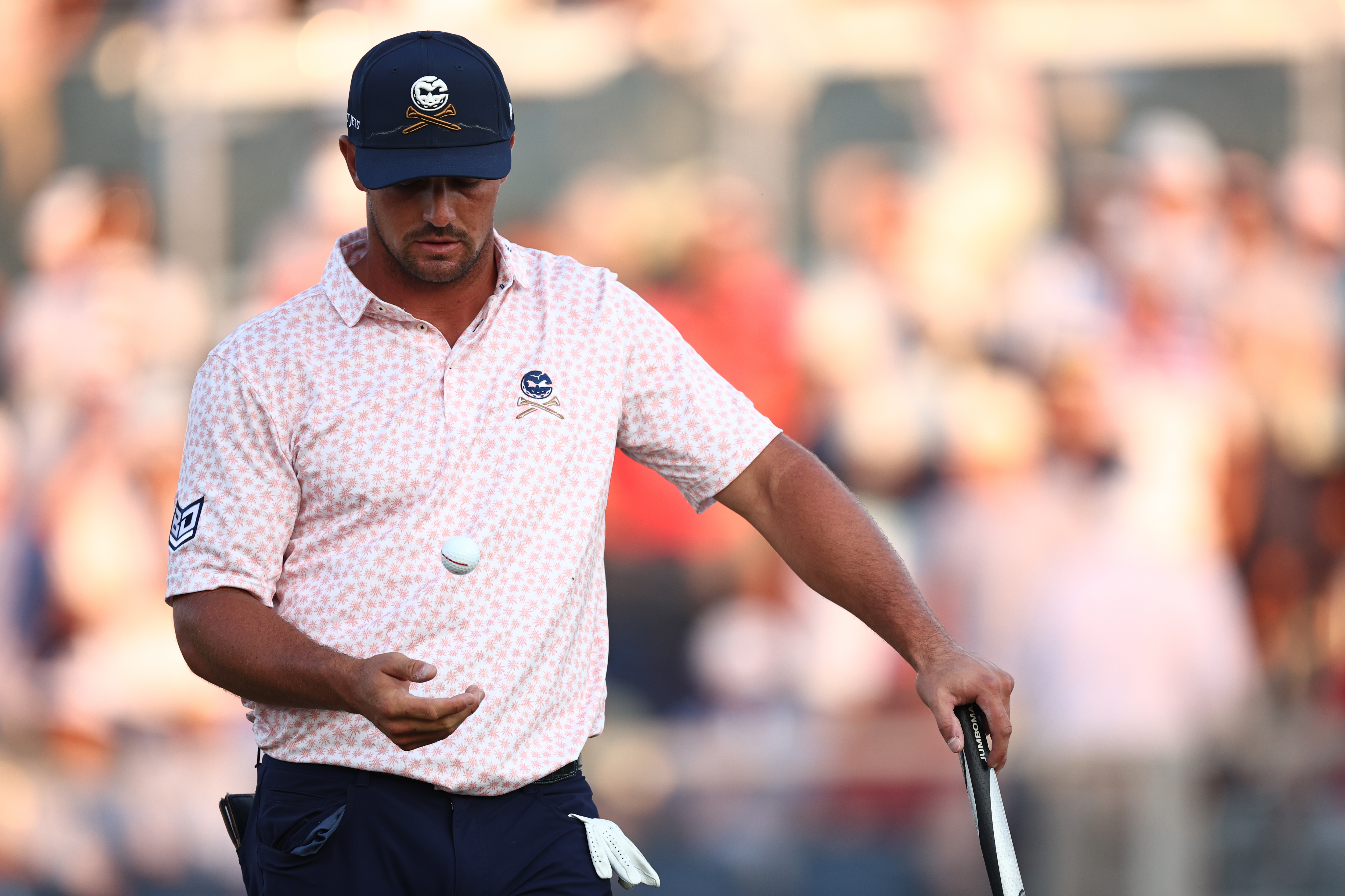Bryson DeChambeau throws his golf ball in the air and catches it