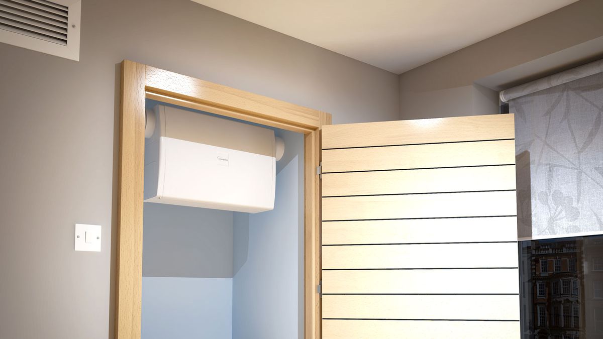 A Nuaire Flatmaster Wall Mounted Positive Input Ventilation unit in cupboard with wooden door