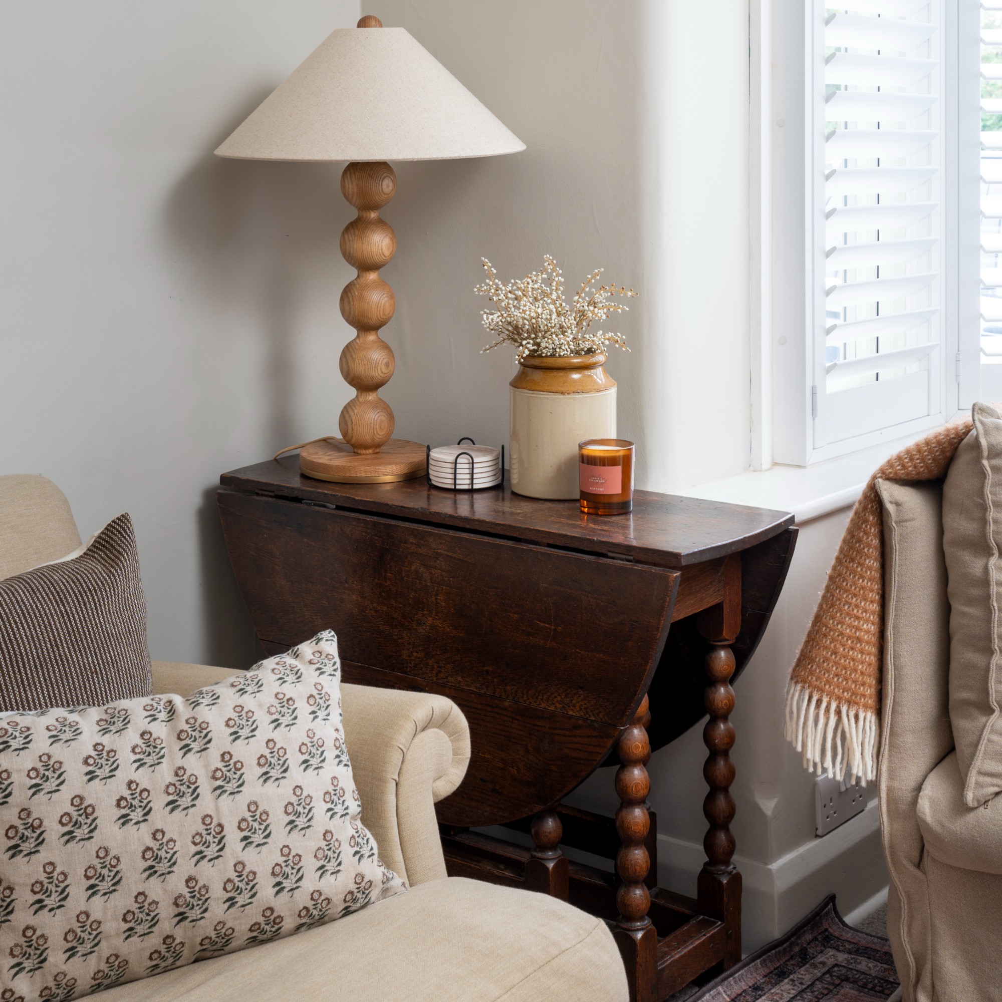 A corner of a living room with a foldable wooden table and a bobbin table lamp on top