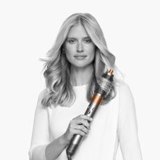 Model holding Dyson airwrap and curling her hair