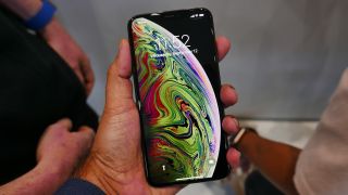 An iPhone XS Max in someone's hand, with the screen on