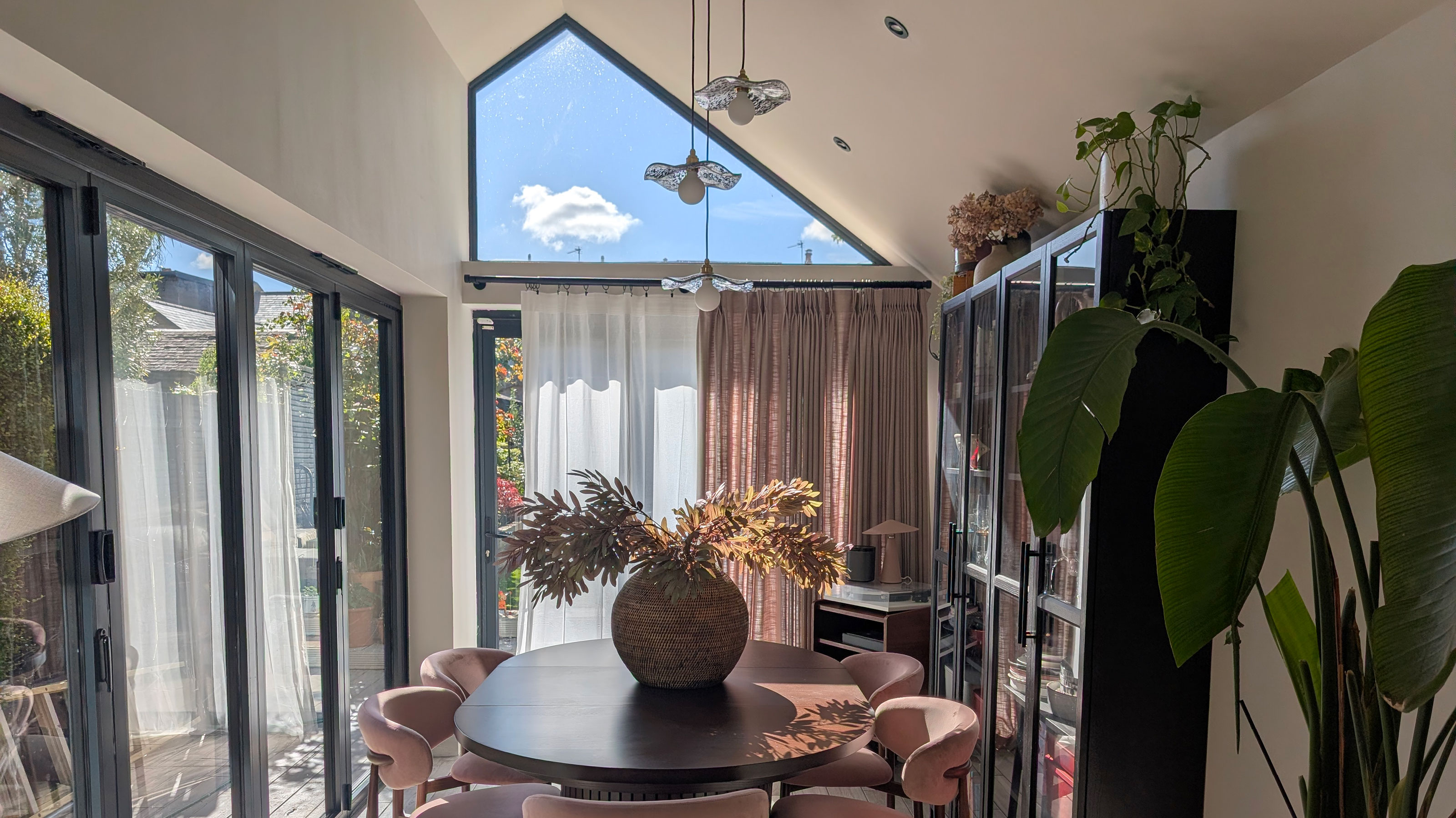 Dining area in extension with pitched roof, wooden table and pink chairs