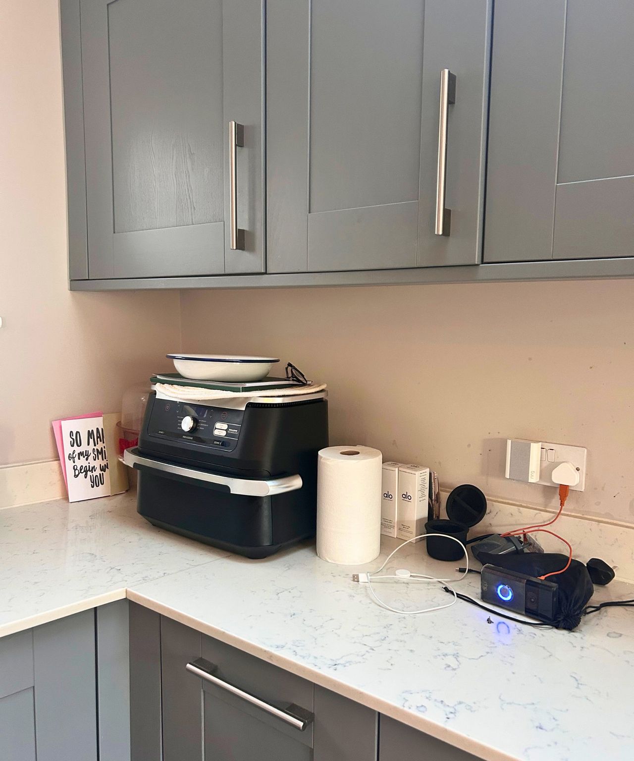 Messy kitchen countertop with a Ninja air fryer, cards and kitchen roll