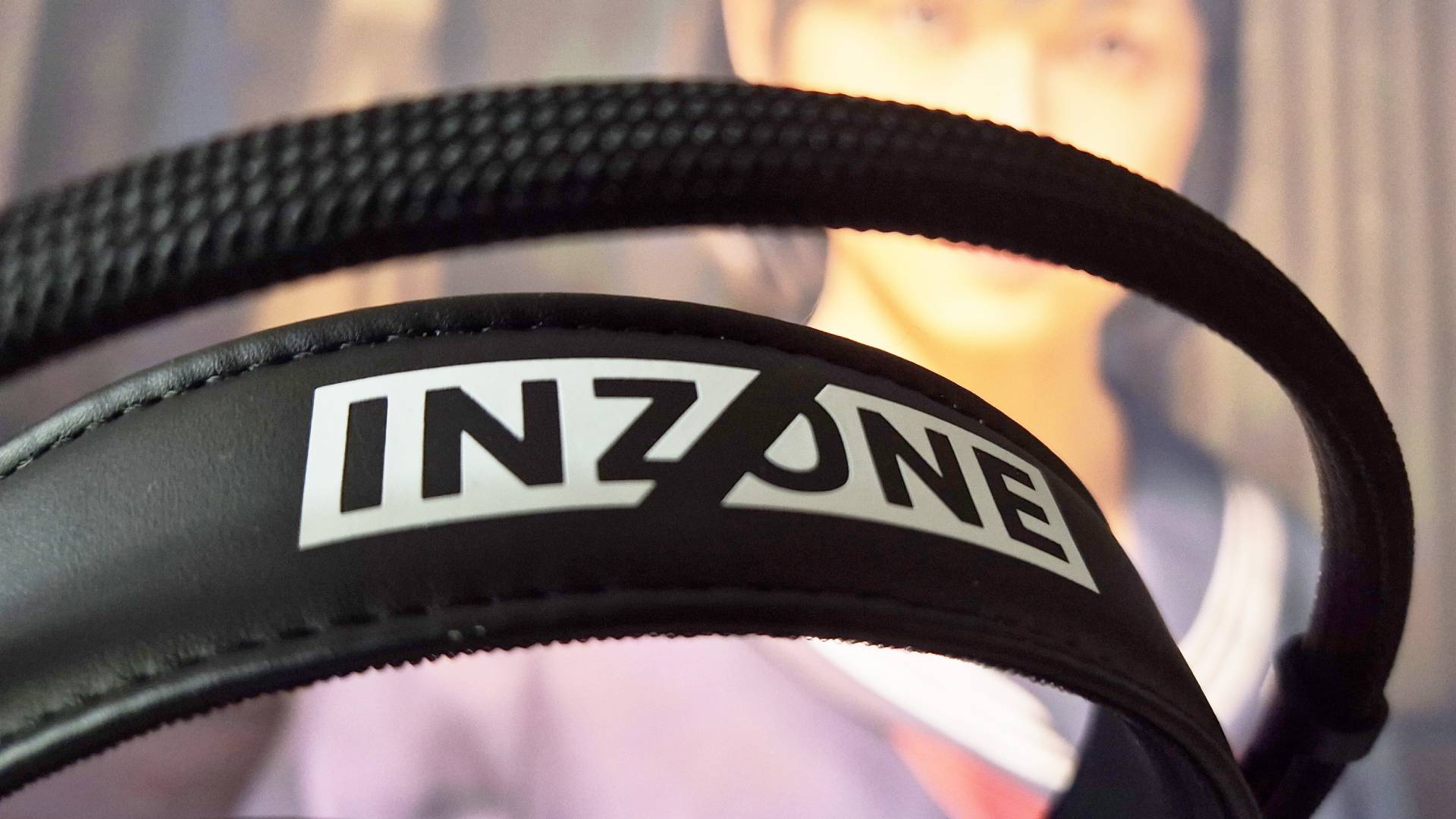 Photo of the headband from a black headset, sitting in front of a TV showing a screenshot from Konami&#039;s Silent Hill f.