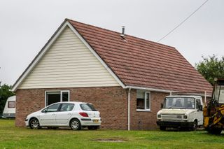 A redbrick bungalow with white cladding and a clay tiled roof