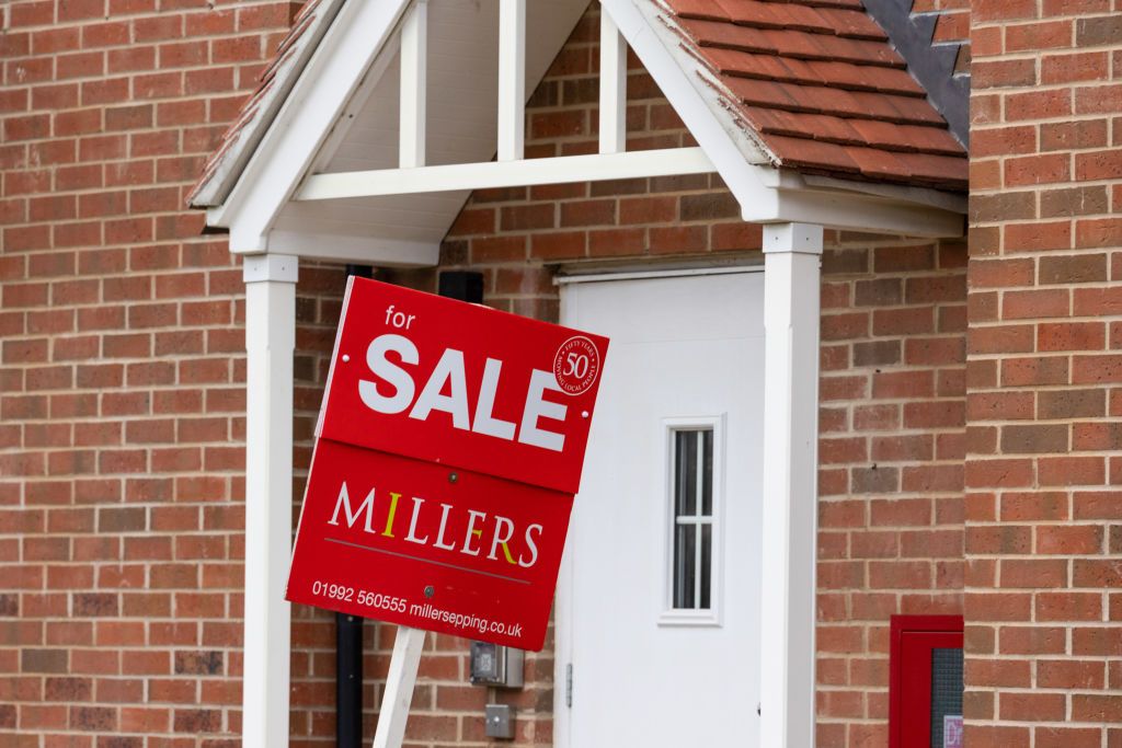 A red for sale sign outside a home&#039;s front door