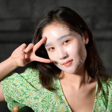 model wearing a sheet mask and making a peace sign