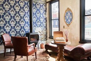 Blue wallpaper and leather furnishings and a typewriter inside the king suite at The Western Hotel in Ouray, Colorado