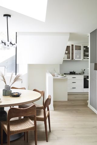 A minimal open plan apartment kitchen with a mid century dining table