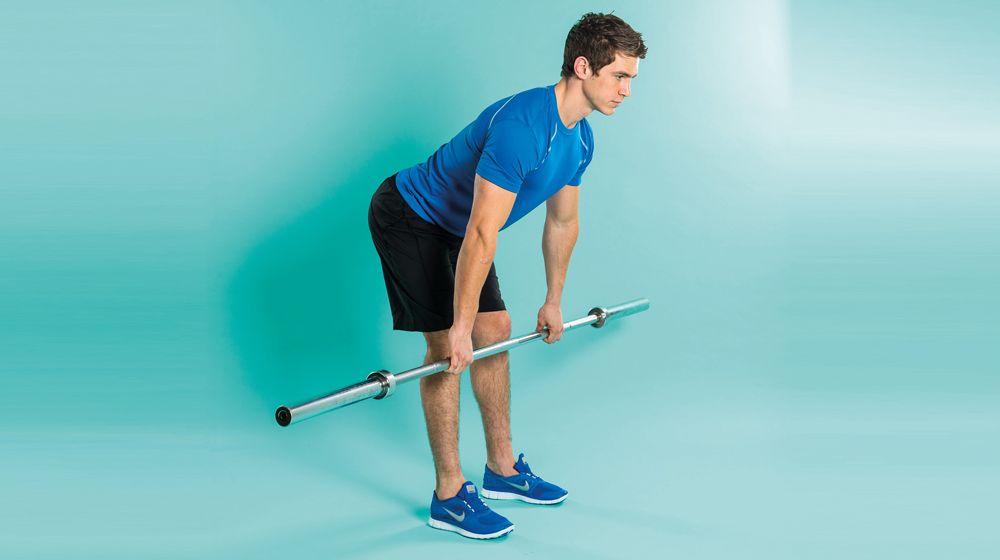 Man demonstrates the midway position of the Romanian deadlift using an empty Olympic barbell