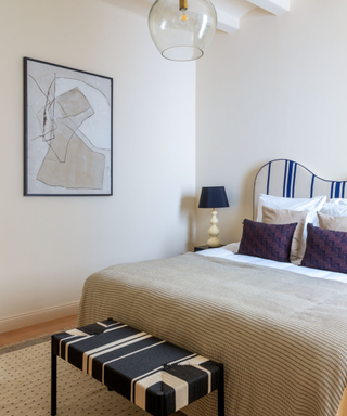 Modern bedroom with unique wave headboard in minimal neutral space with pops of color in art