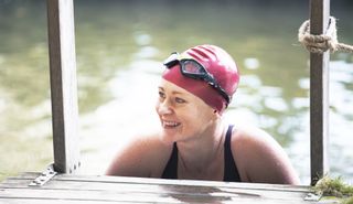 A woman in a swimming cap getting out of a lake