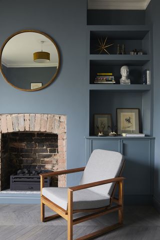Small room painted chalky blue with a bare stone fireplace